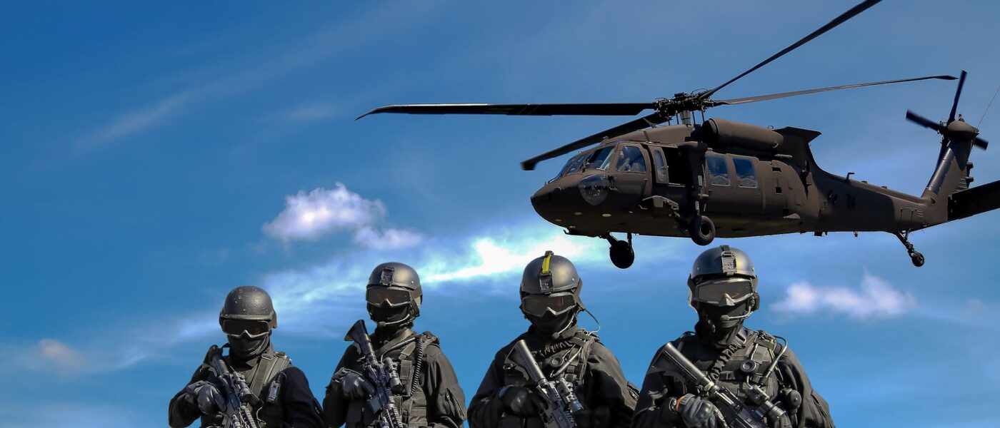 four soldiers carrying rifles near helicopter under blue sky