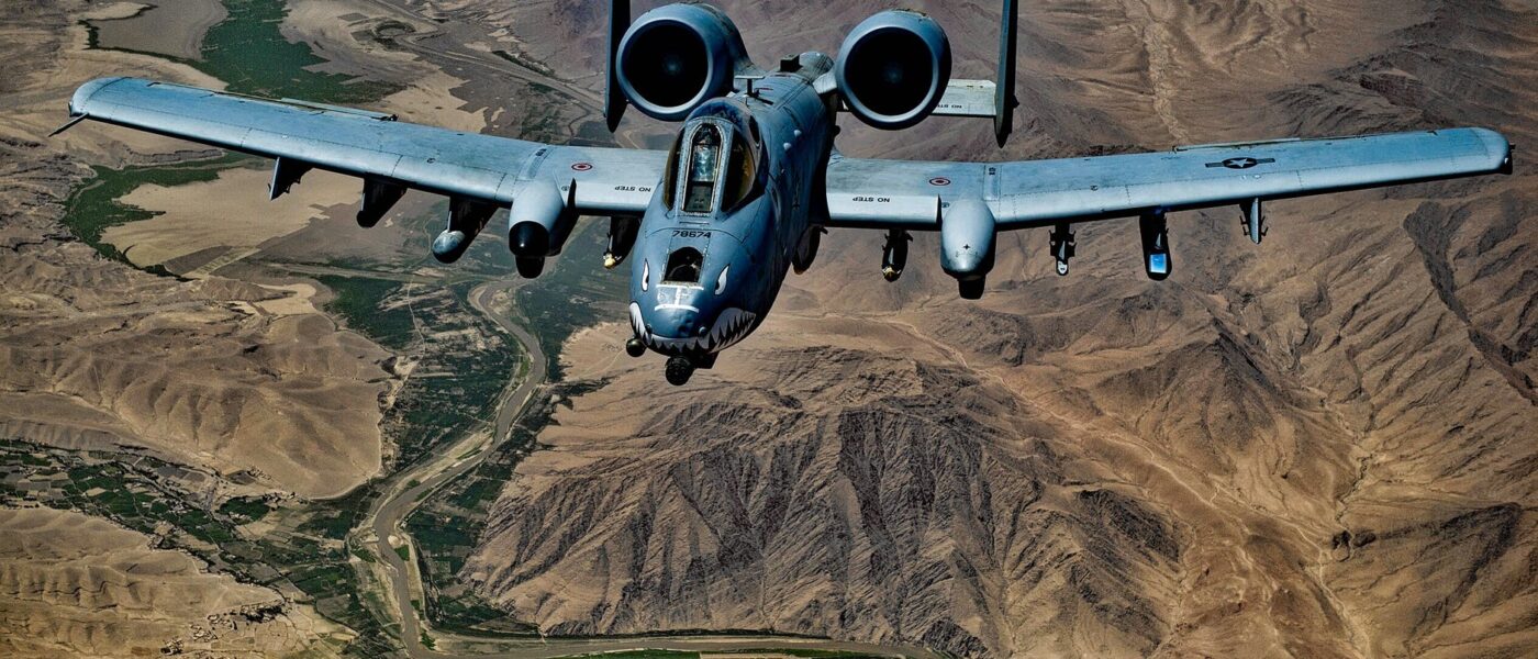 gray jet fighter flying above brown mountain