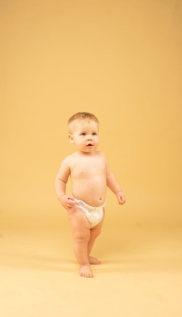 baby standing in front of yellow background